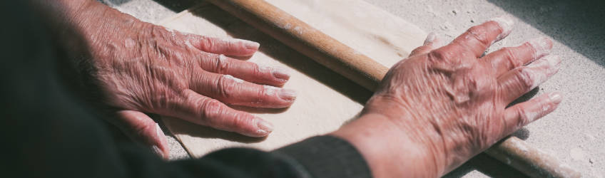Older hands rolling dough